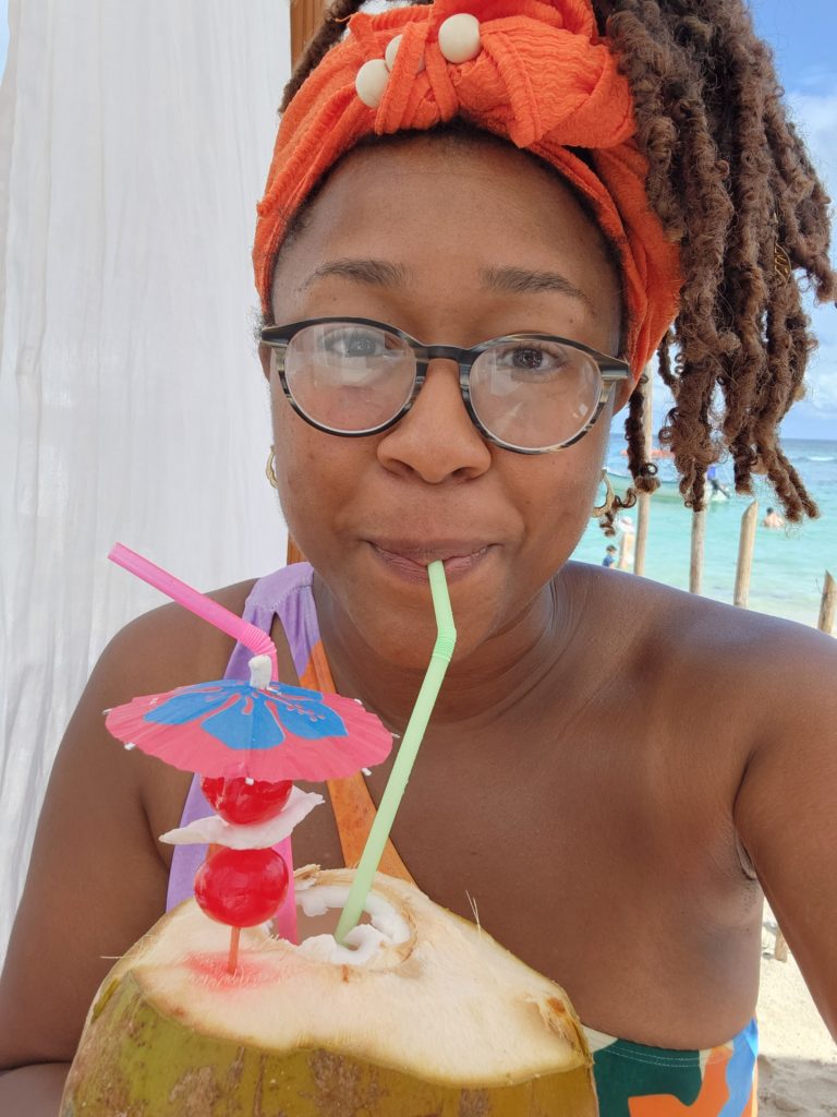 Chaundra drinking from a coconut on the beach. 
