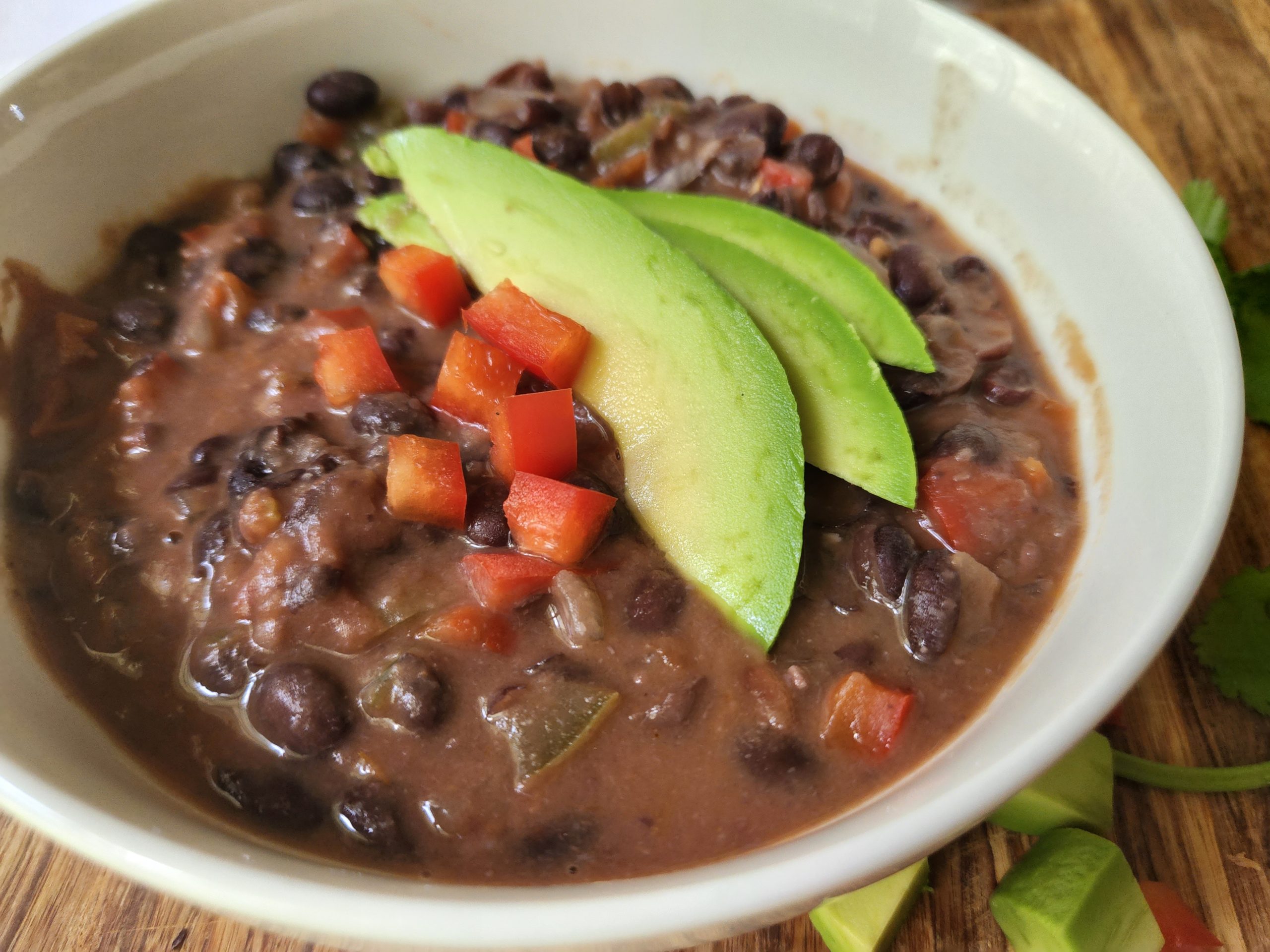 Black Bean Soup in a white bowl, avocado topping.